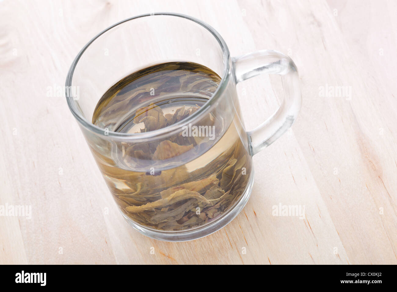 Tasse en verre de thé vert avec des feuilles, closeup on wooden table Banque D'Images