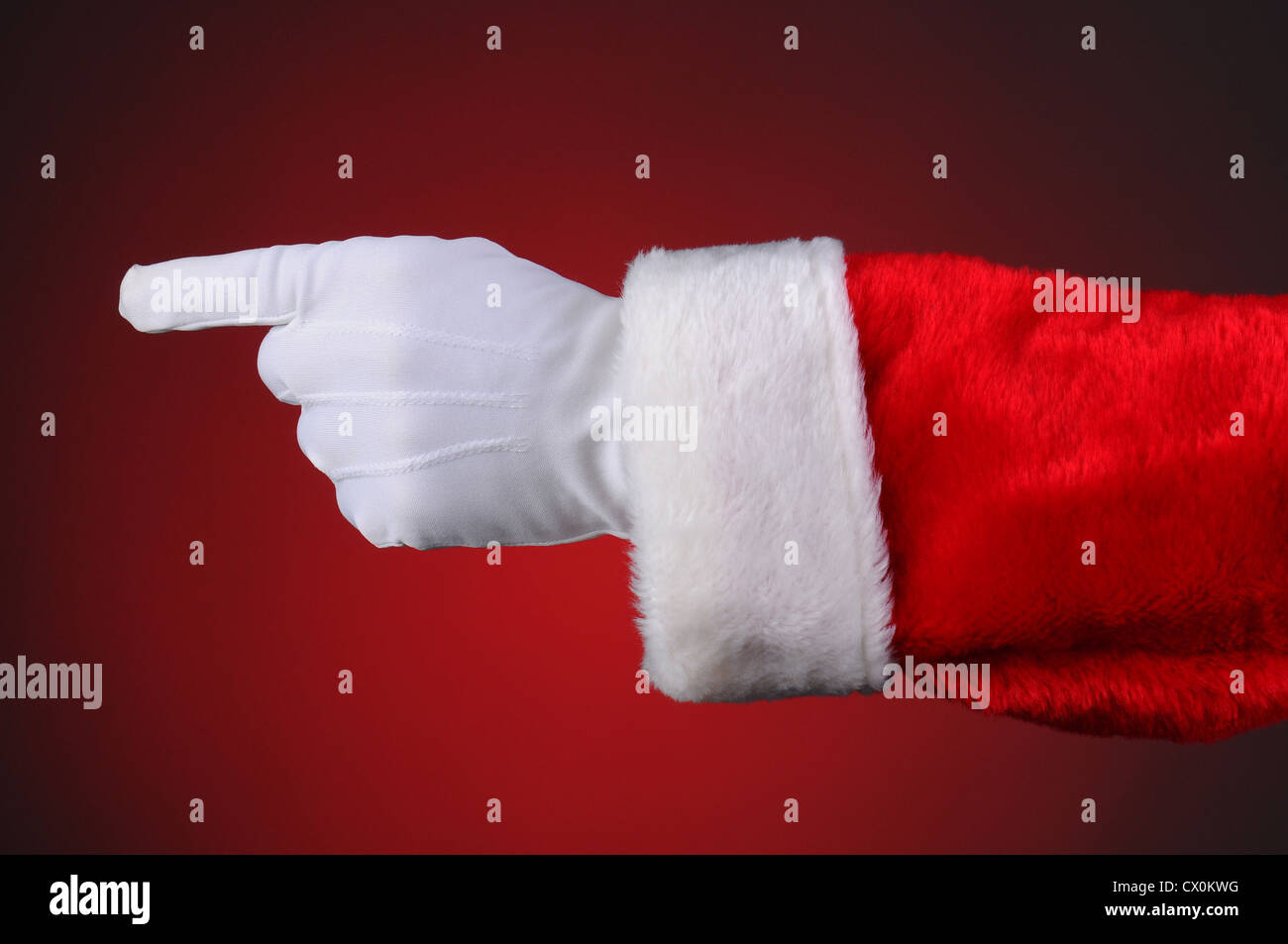 Père Noël qui pointe, mains et bras seulement. Format horizontal sur un fond rouge clair à foncé. Banque D'Images