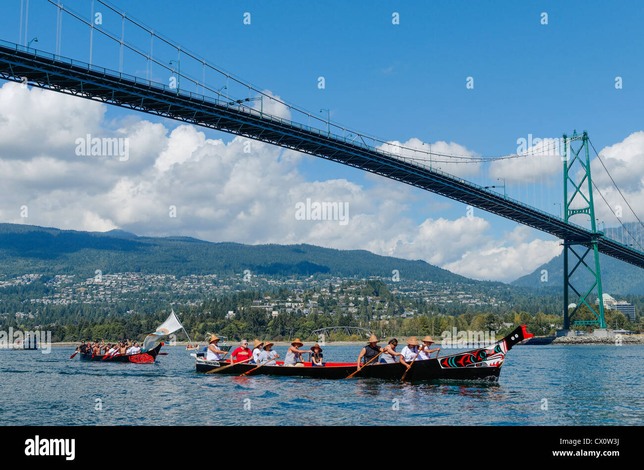 Les canots de la Première Nation Salish de la côte et des pagayeurs passent sous le pont Lions Gate, West Vancouver, BC, Canada Banque D'Images