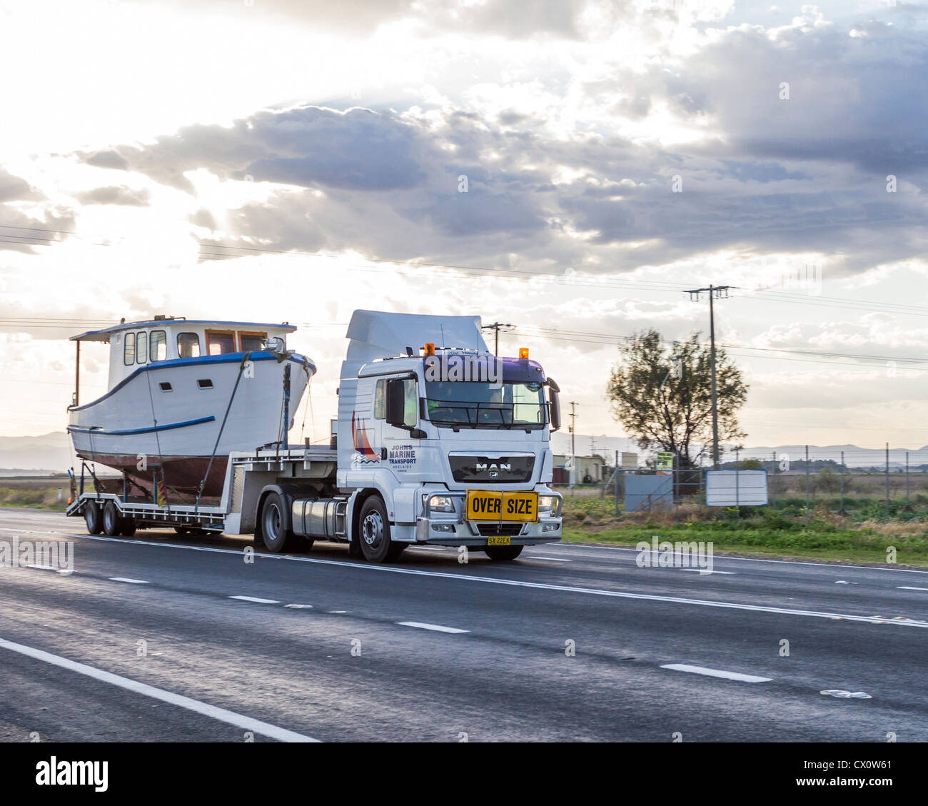 Camion semi-remorque surdimensionnée transport grand bateau tôt le matin en NSW, Australie Outback Banque D'Images