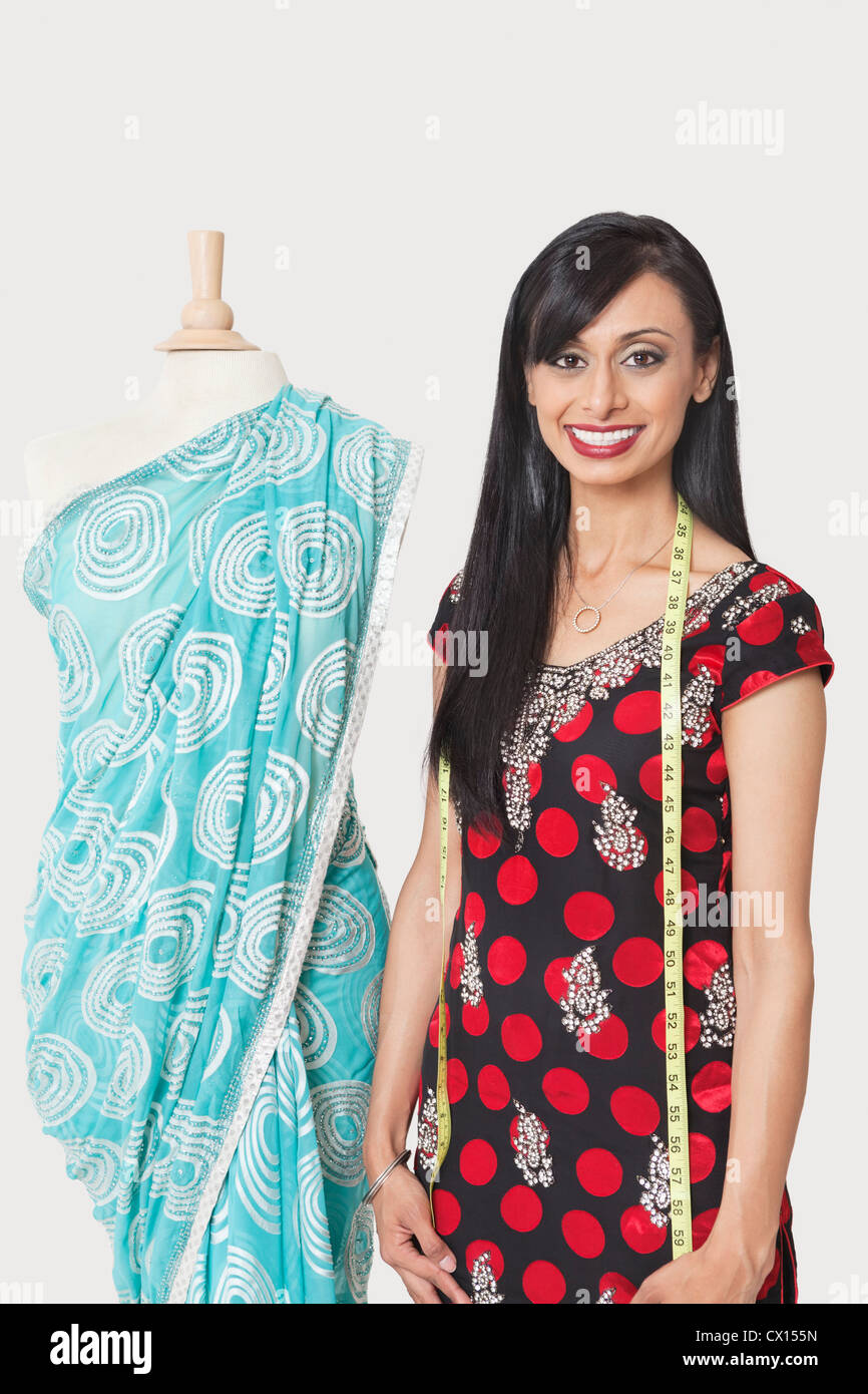 Portrait of happy Indian female fashion designer standing par dummy drapée dans un sari Banque D'Images