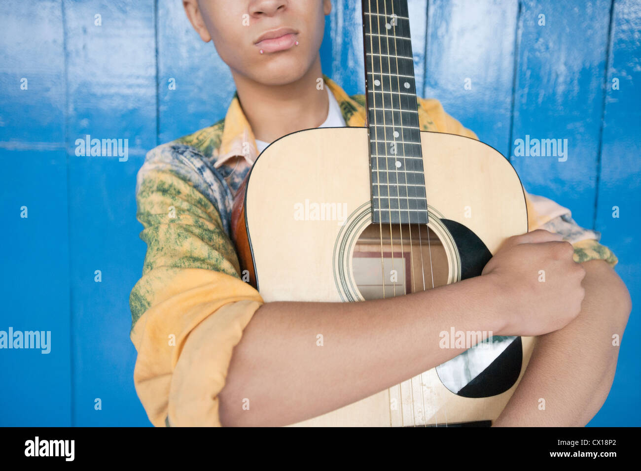Mid section of a Teenage boy avec guitare contre des lambris Banque D'Images