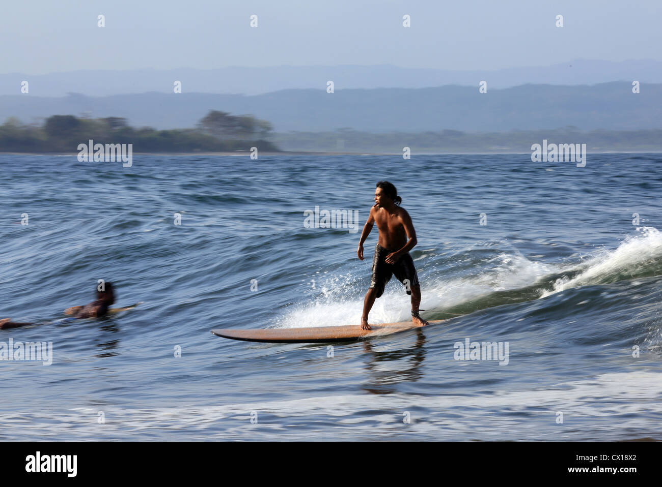 Javanais Local surf surfer une vague en Batu Karas, l'Ouest de Java, en Indonésie. Banque D'Images