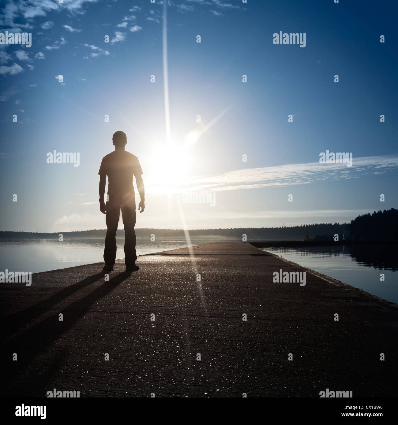 Un homme se tient sur la jetée en béton avec au Soleil Couchant Banque D'Images