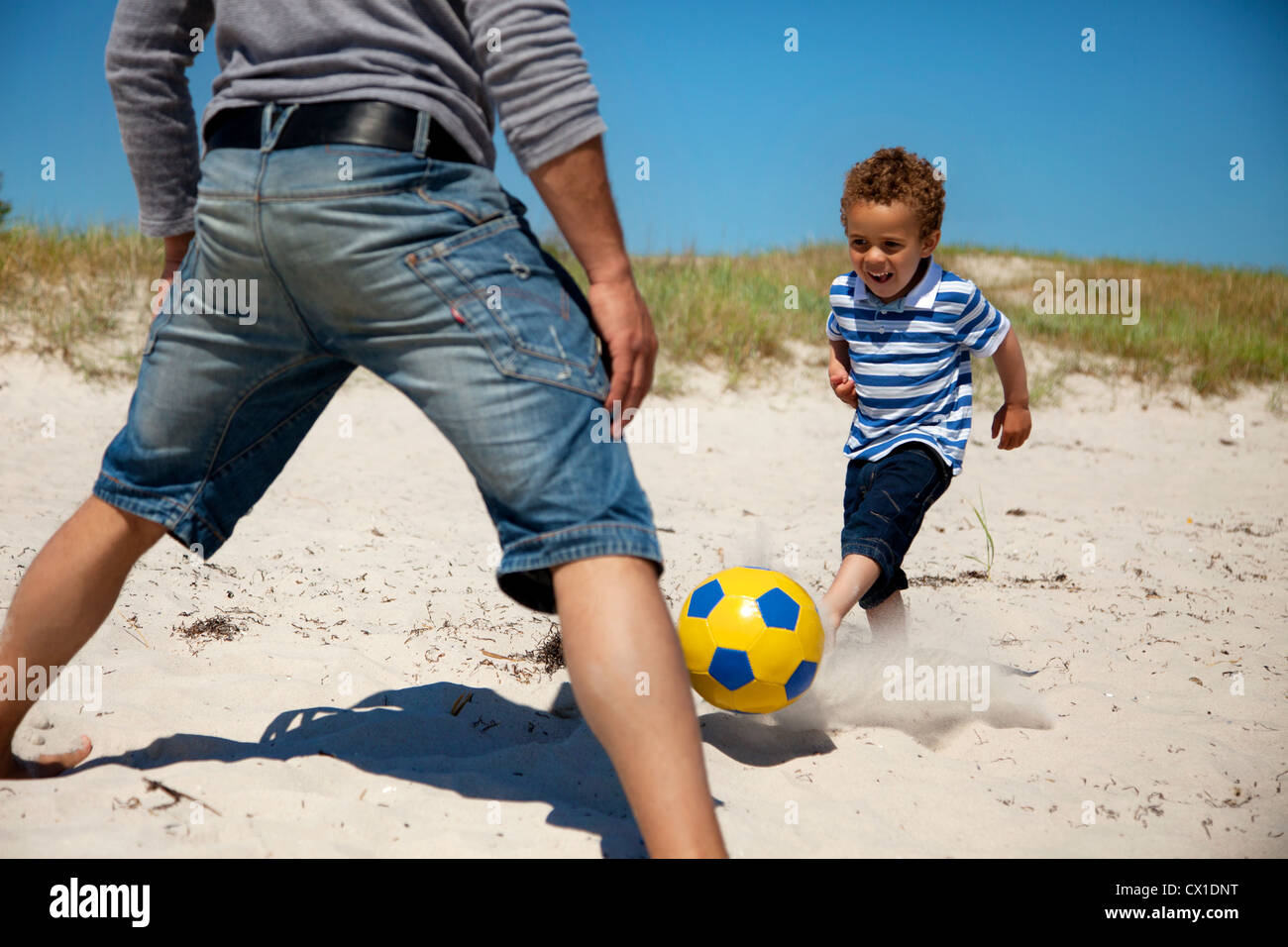 Père avec son jeune fils à jouer au football sur la plage Banque D'Images