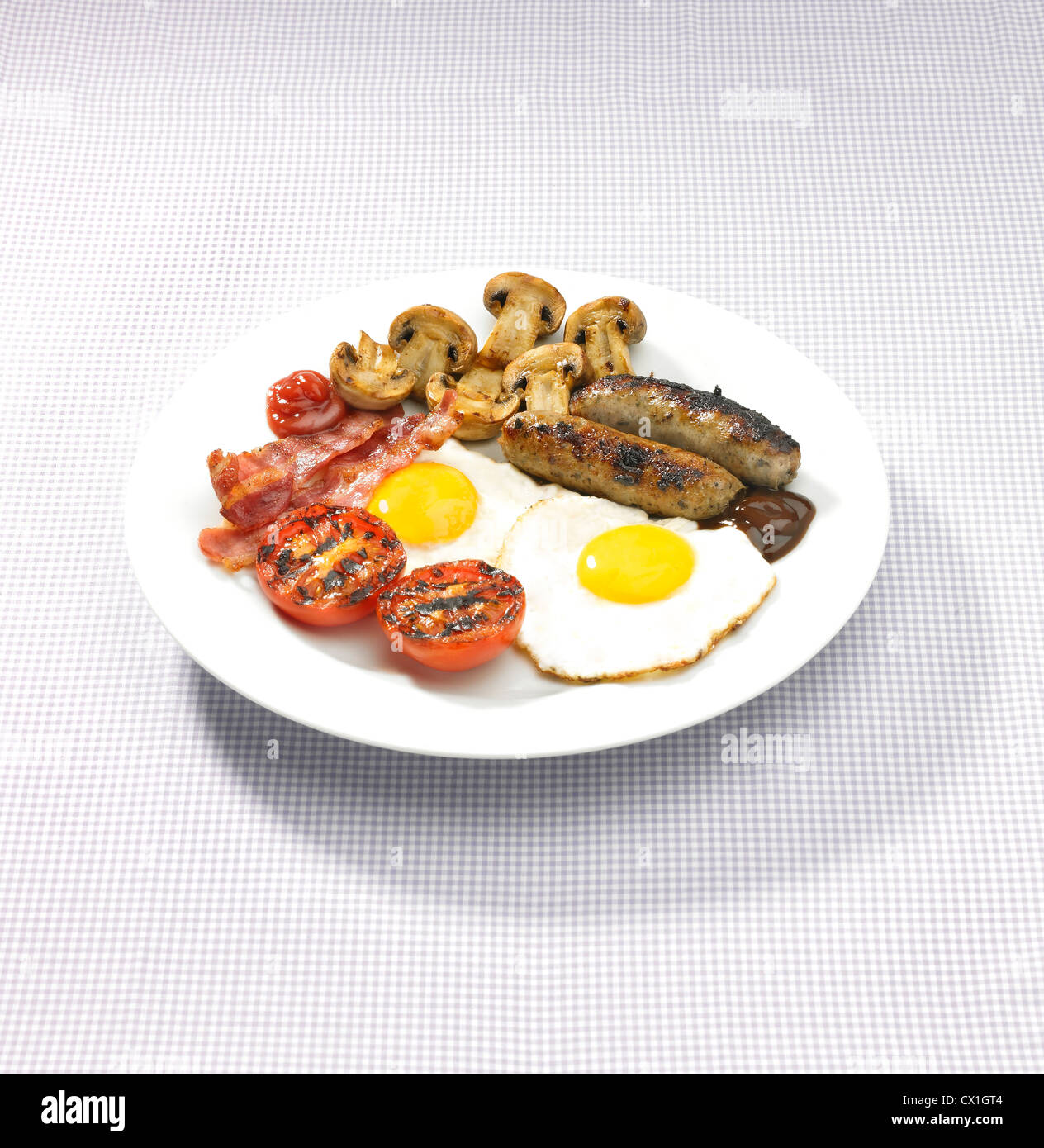 Un petit-déjeuner anglais complet servi sur une plaque blanche sur du matériel à damier table top Banque D'Images