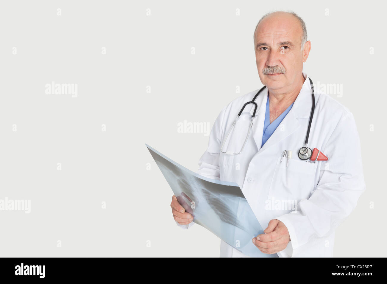 Portrait of senior homme médecin holding x-ray sur fond gris Banque D'Images