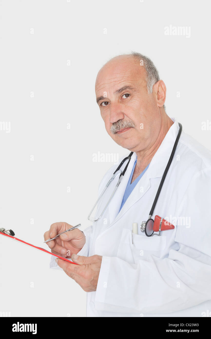 Portrait of senior médecin avec presse-papiers sur fond gris Banque D'Images