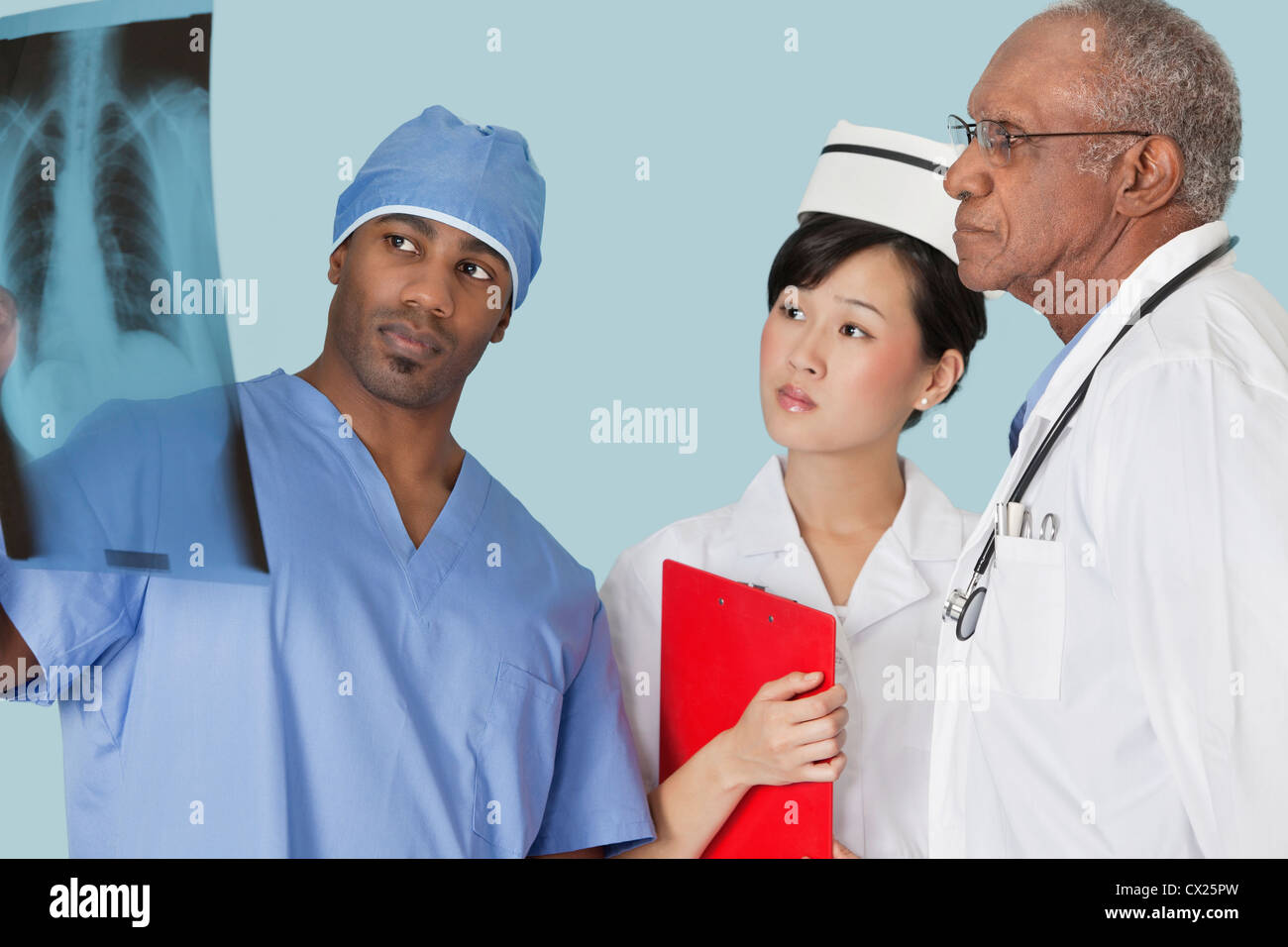 Multi Ethnic doctors examining x-ray report sur fond bleu clair Banque D'Images