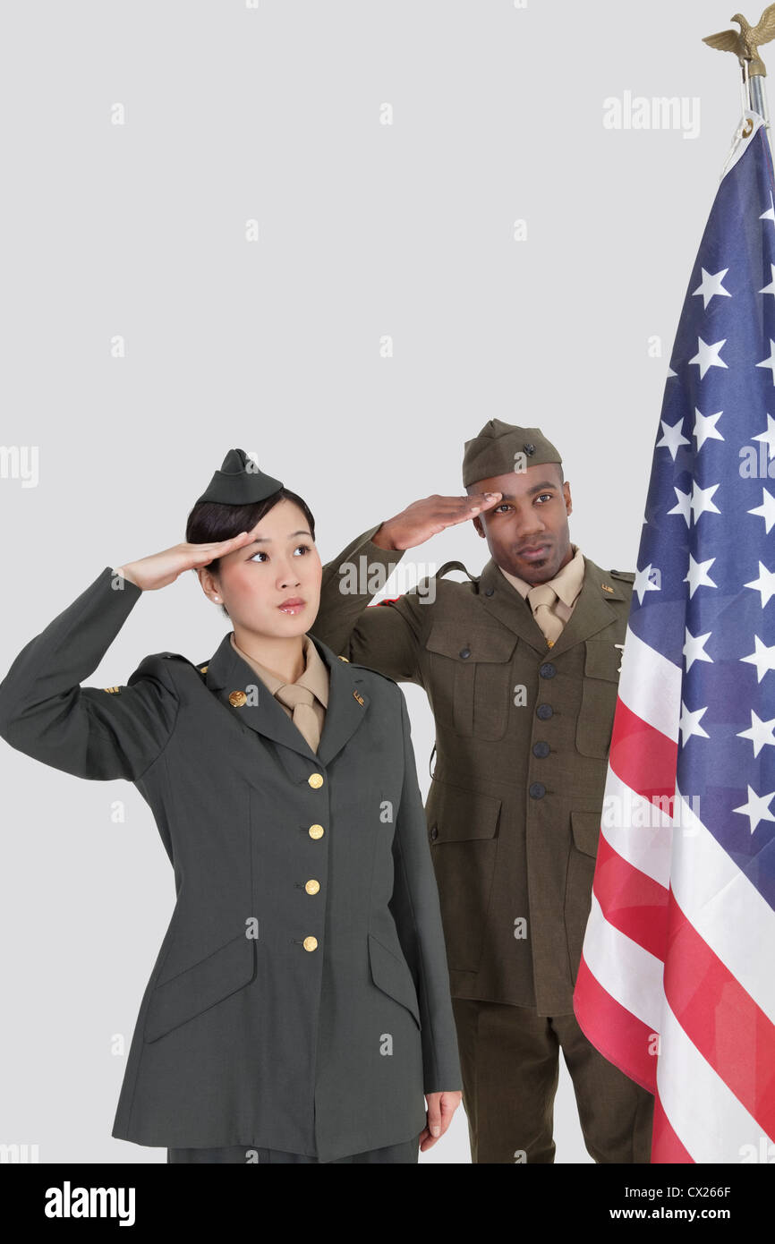 Nous multi-ethnique des officiers militaires saluant drapeau américain sur fond gris Banque D'Images