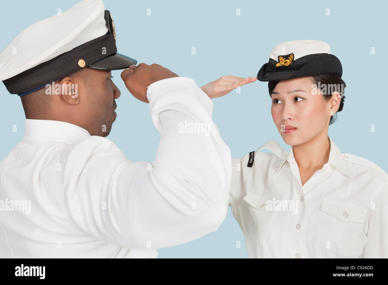 Nous multi-ethnique de la Marine en saluant l'autre sur fond bleu clair Banque D'Images