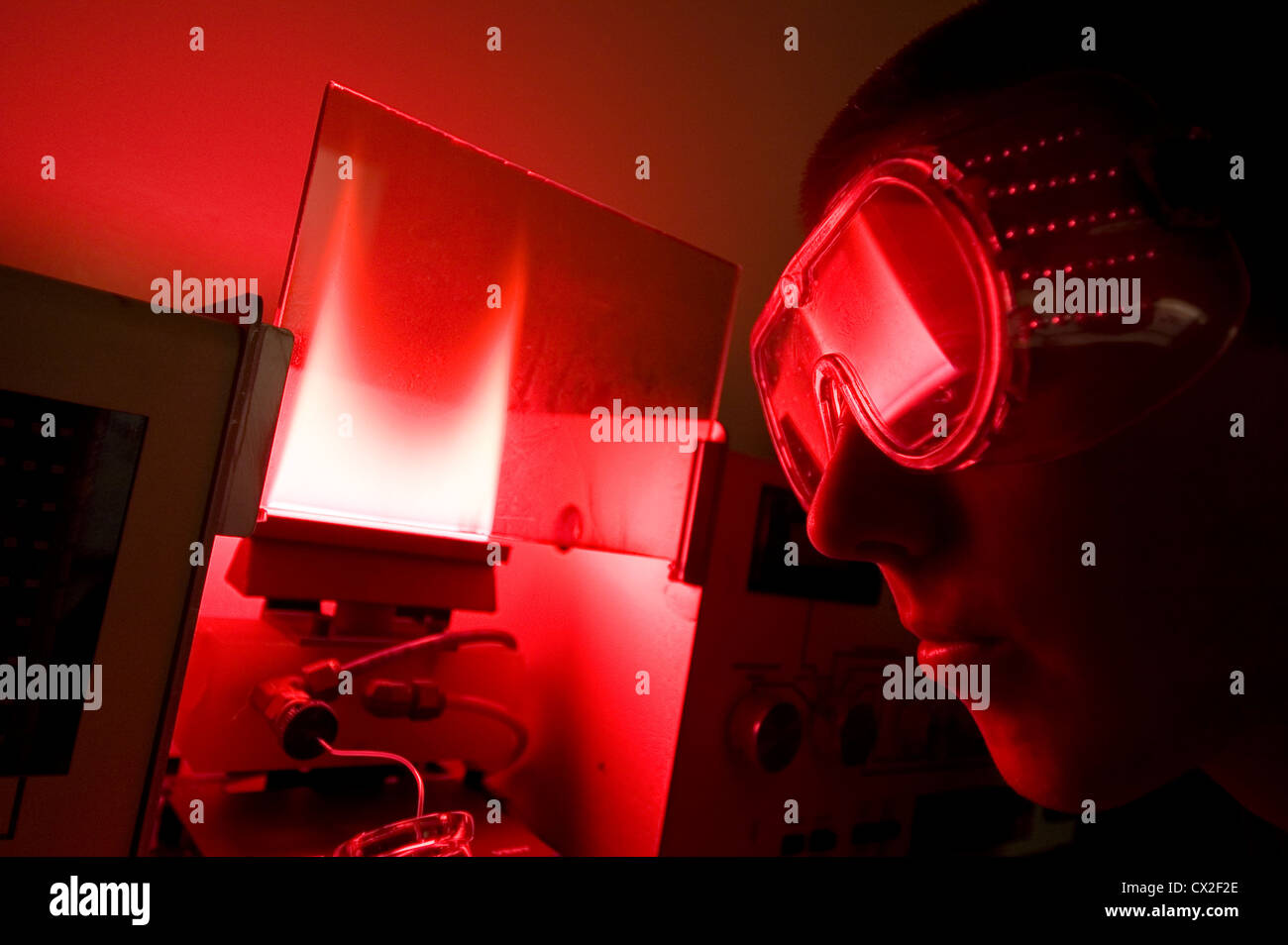 Un étudiant baigné dans la lueur rouge d'un chromatographe en phase gazeuse Banque D'Images