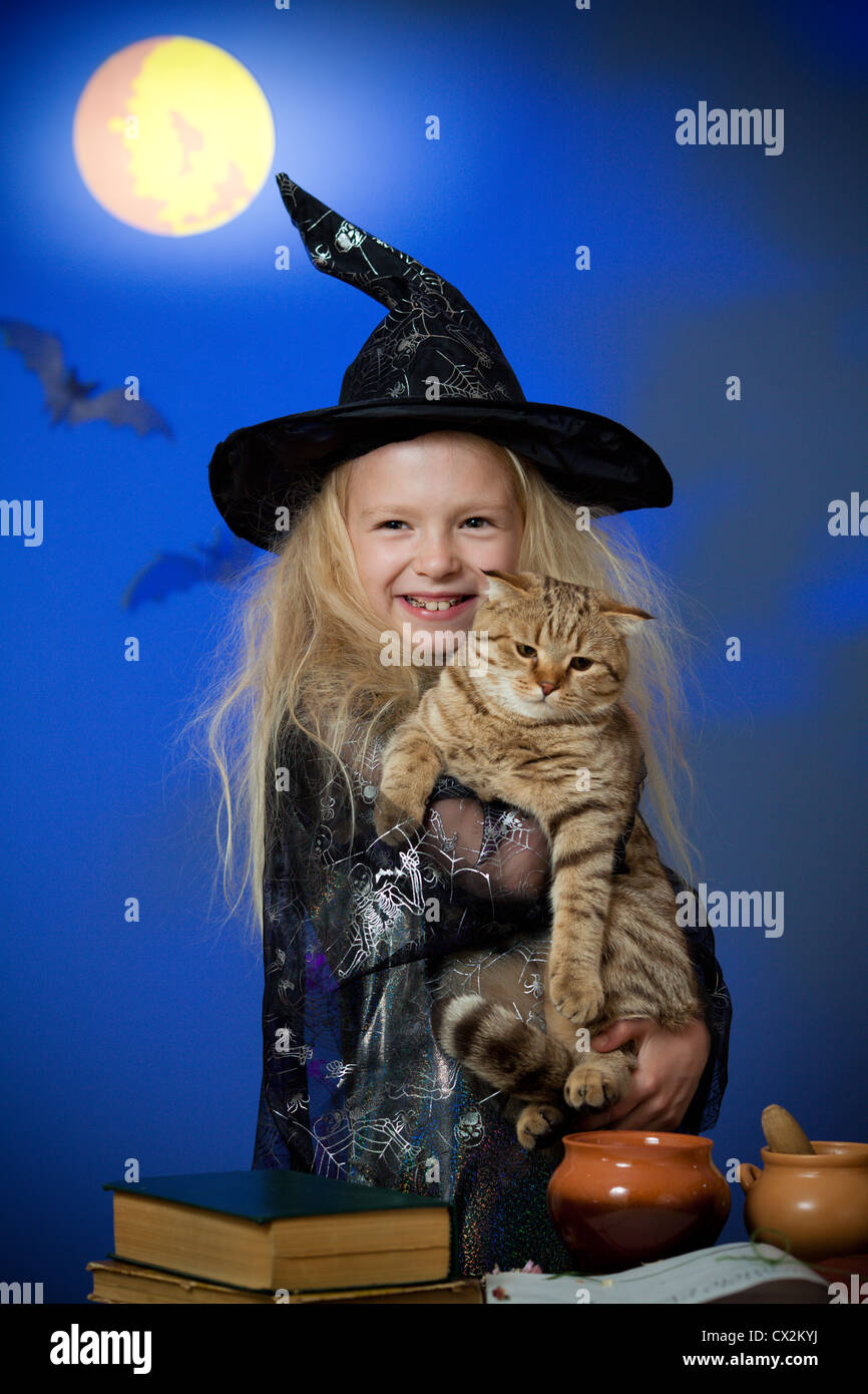 Fille déguisée en sorcière dans nuit avec cat Banque D'Images