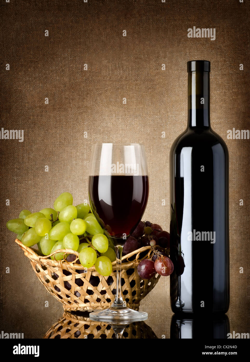 Bouteille de vin rouge et les raisins sur une toile de fond Banque D'Images