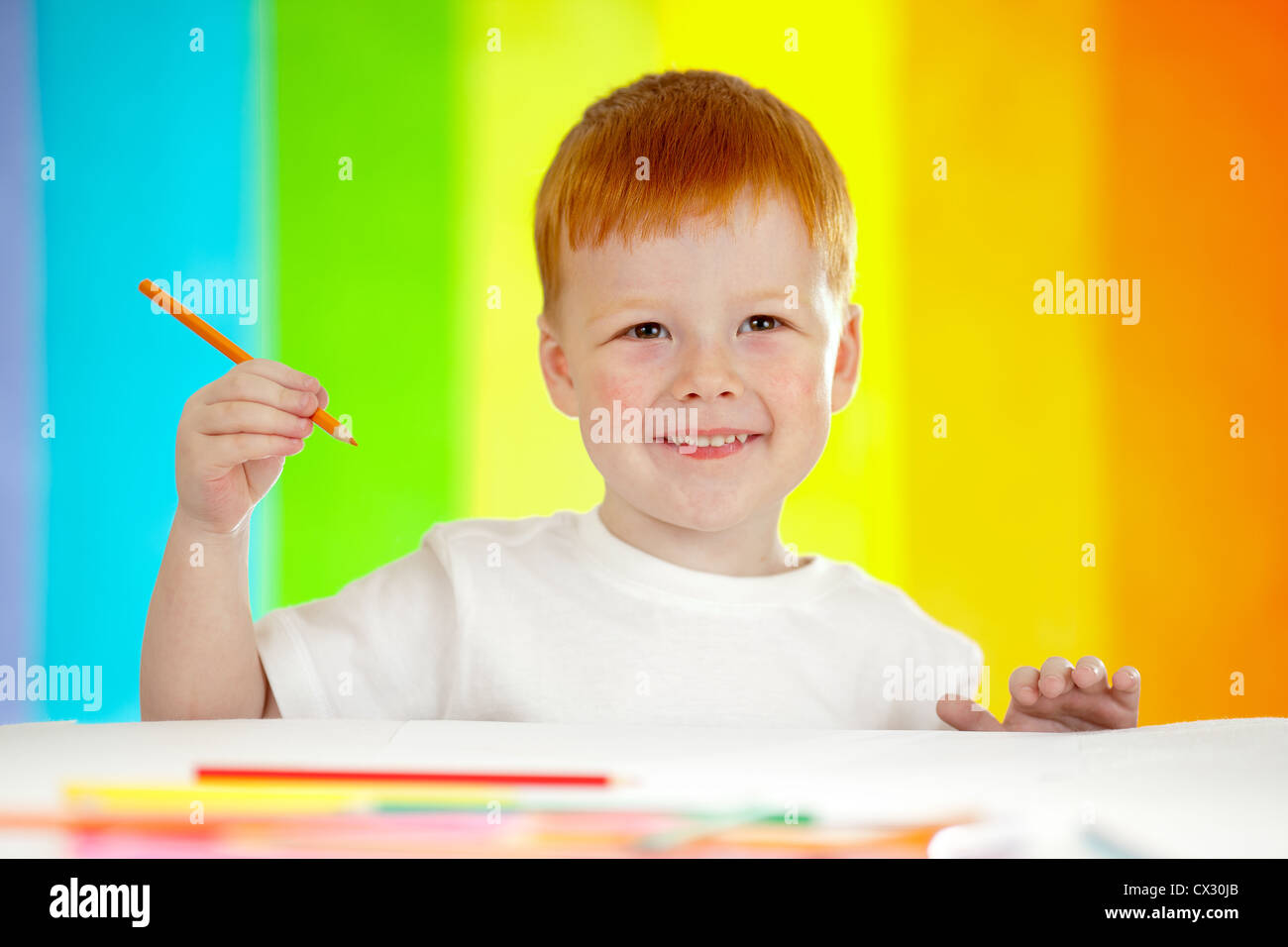 Red-haired boy adorable dessin avec crayon orange sur fond arc-en-ciel Banque D'Images