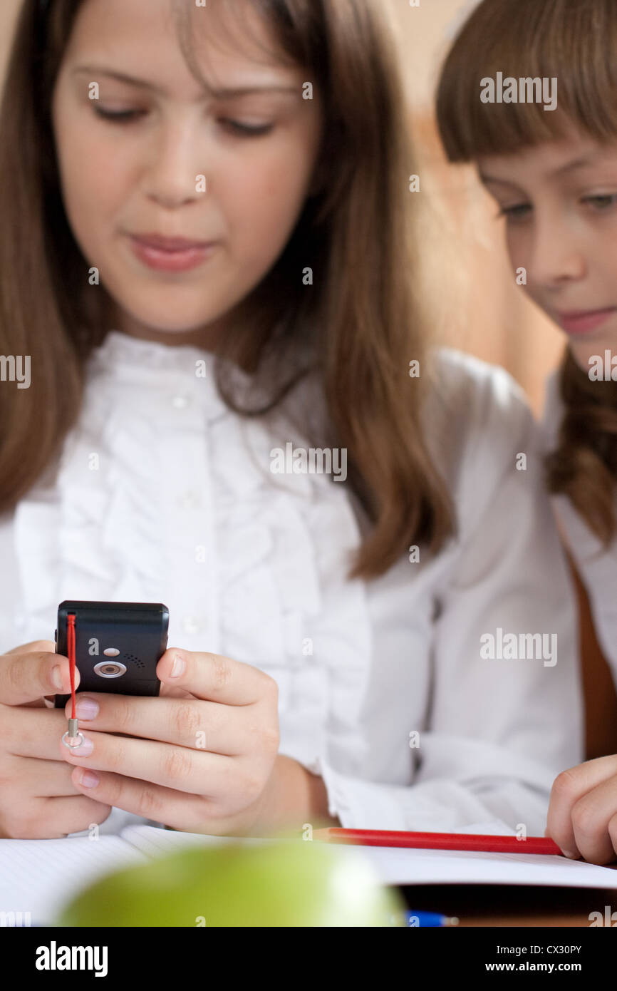 Deux filles sont à l'aide de téléphone mobile avec intérêt Banque D'Images