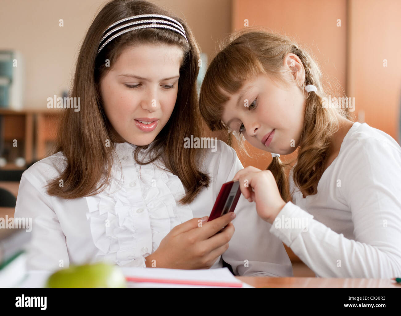 Deux jeunes filles à l'école séance bureau avec téléphone mobile Banque D'Images