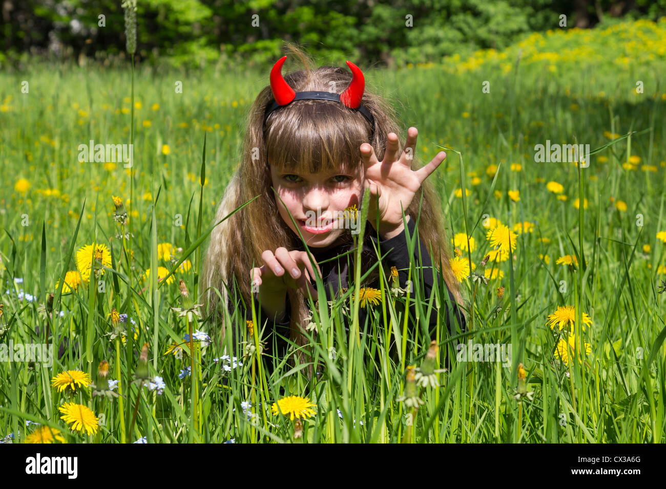 Petit diable fille dans un champ de pissenlit vert Banque D'Images
