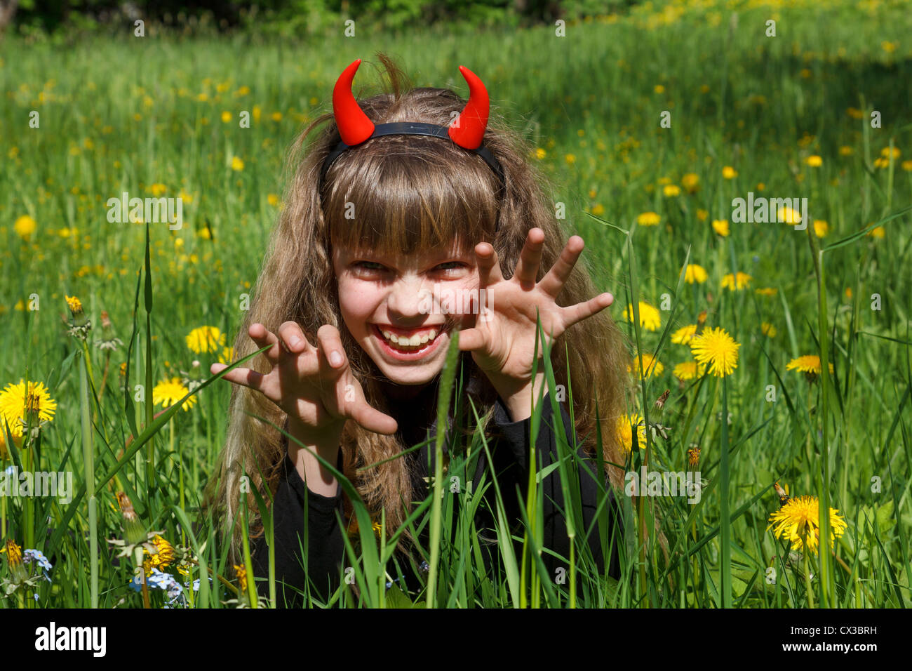 Petit diable fille dans un champ de pissenlit vert Banque D'Images