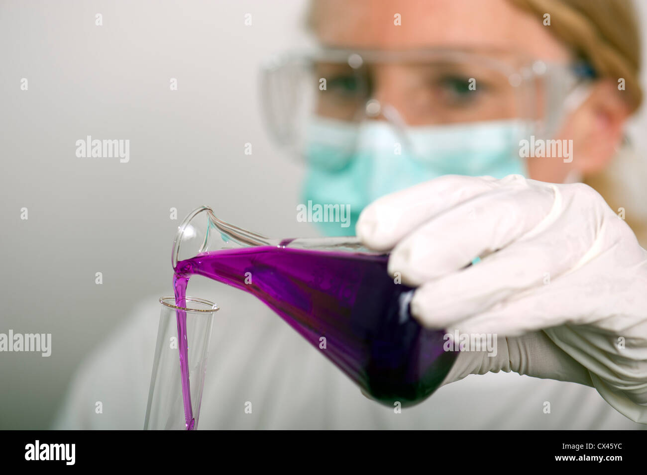 Chimiste s'incline du liquide d'un fiole dans un tube à essai Banque D'Images