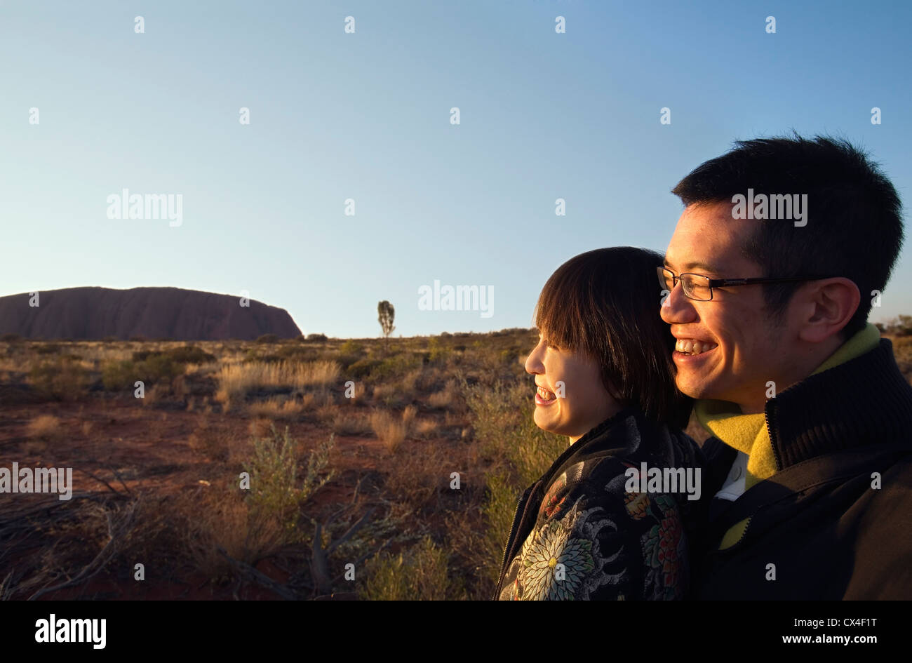 Un couple asiatique regarder le lever du soleil sur Uluru (Ayers Rock). Le Parc National d'Uluru-Kata Tjuta, Territoire du Nord, Australie Banque D'Images
