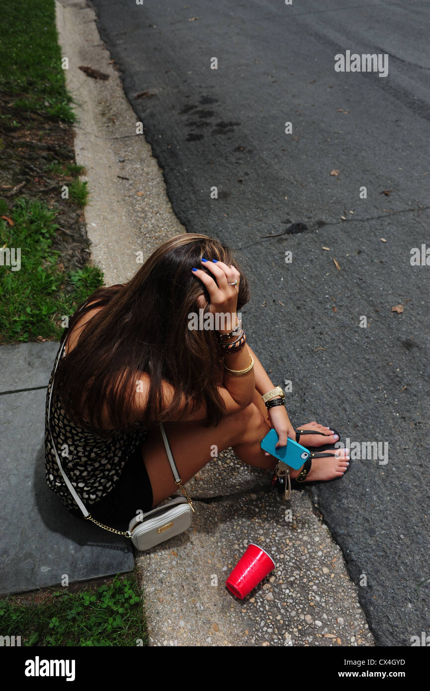 Teenage girl sitting sur le trottoir d'une rue - contrarié déprimé triste underage drinking Banque D'Images