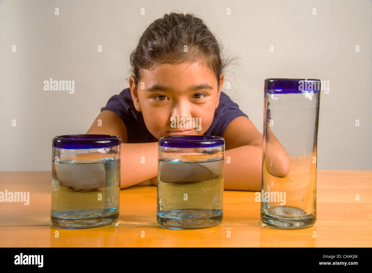 Un enfant regarde verres identiques remplis de la même quantité de liquide à démontrer l'expérience de Piaget Conservation liquide. Banque D'Images
