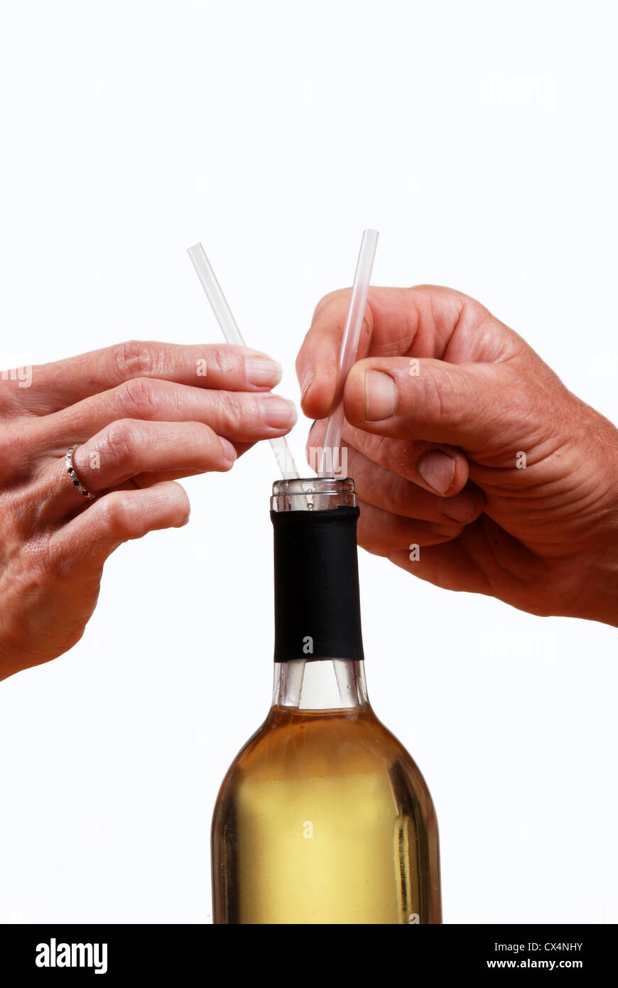 Libre de l'homme et de la femme mains tenant les pailles qui sont dans une bouteille de vin. Banque D'Images