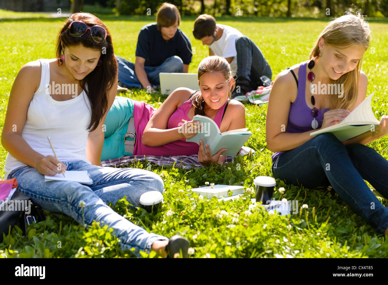 Les adolescents qui étudient au park livre lecture heureux étudiants campus recherche Banque D'Images