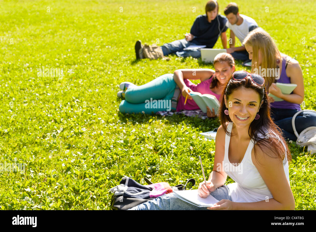 Les étudiants qui étudient sitting on grass in park campus ados heureux Banque D'Images