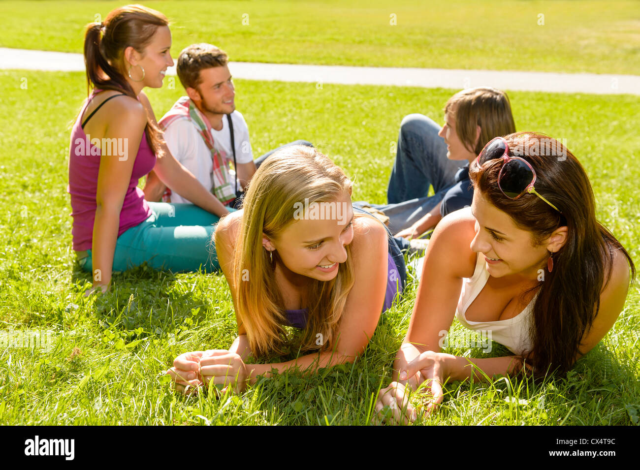 Les adolescents parler relaxing on grass in park heureux amis étudiants Banque D'Images
