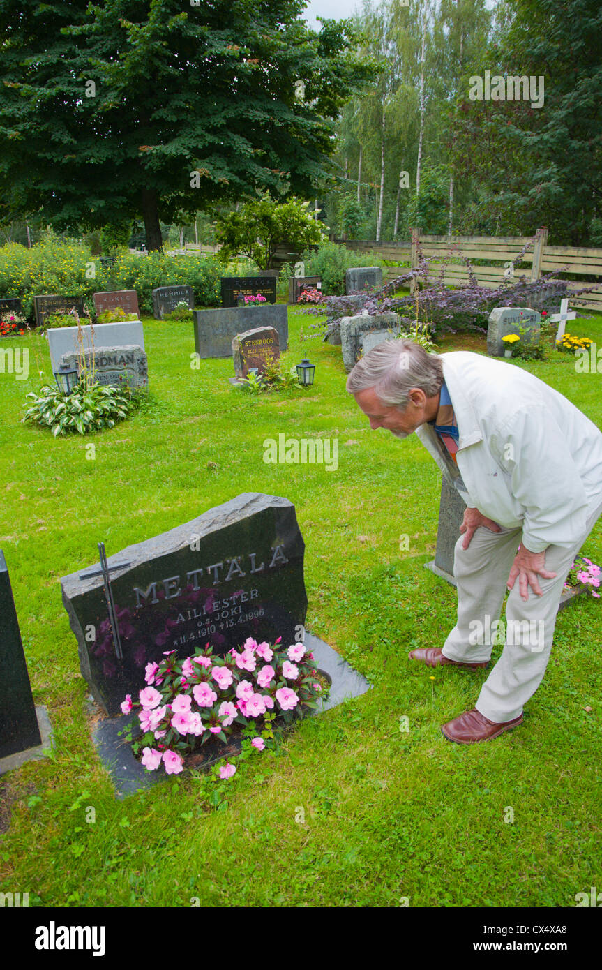 L'homme dans son 70s par la tombe d'un parent au cimetière à Reposaari island Ville de Pori Satakunta Finlande Europe de l'ouest comté Banque D'Images