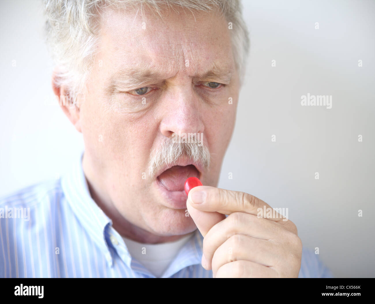 Un homme plus âgé prend une pastille de la gorge pour un mal de gorge Banque D'Images