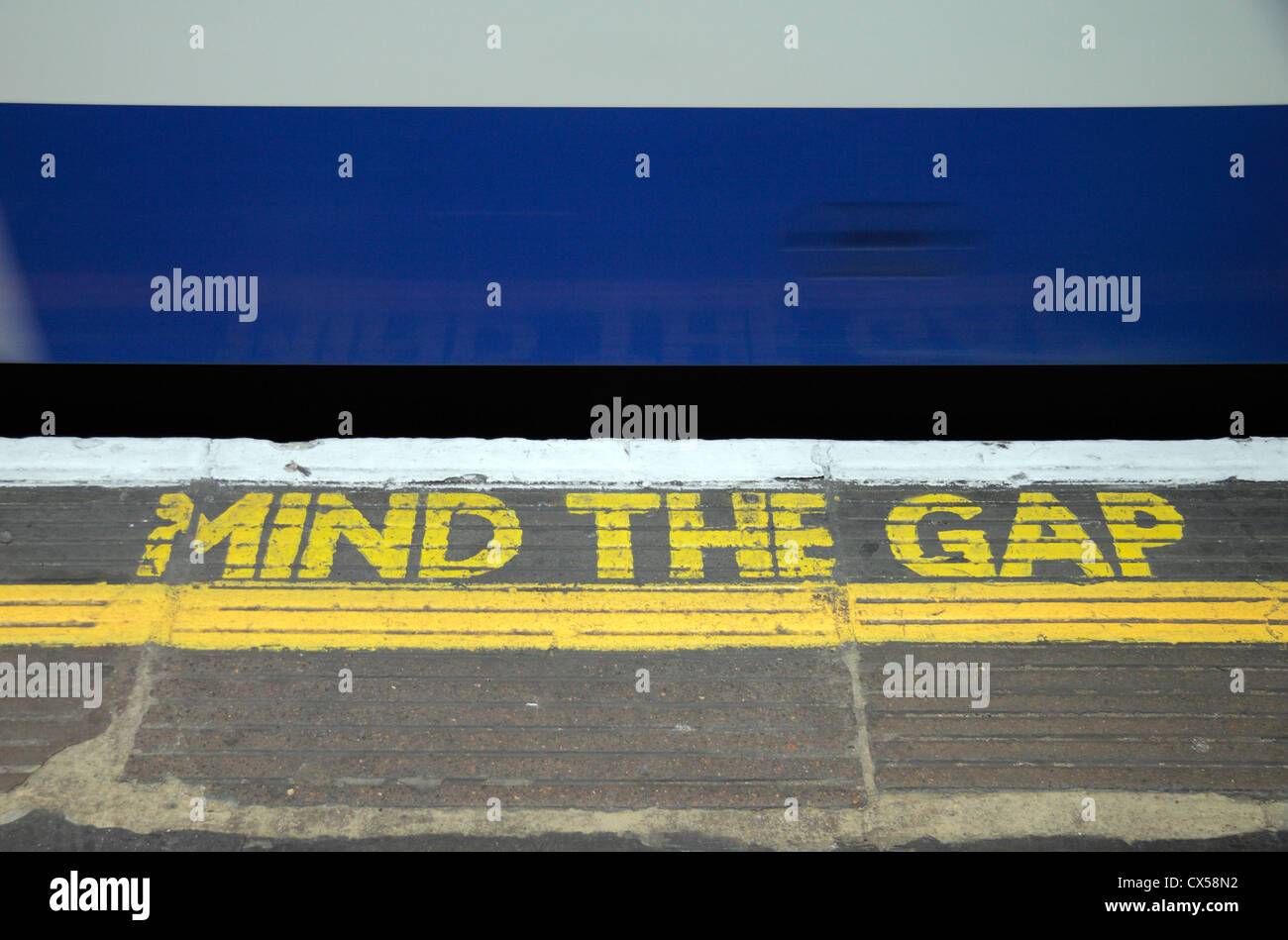 Un excès de Londres métro passant un 'Mind l'écart' signe sur le bord de la plate-forme, Londres, Royaume-Uni. Banque D'Images