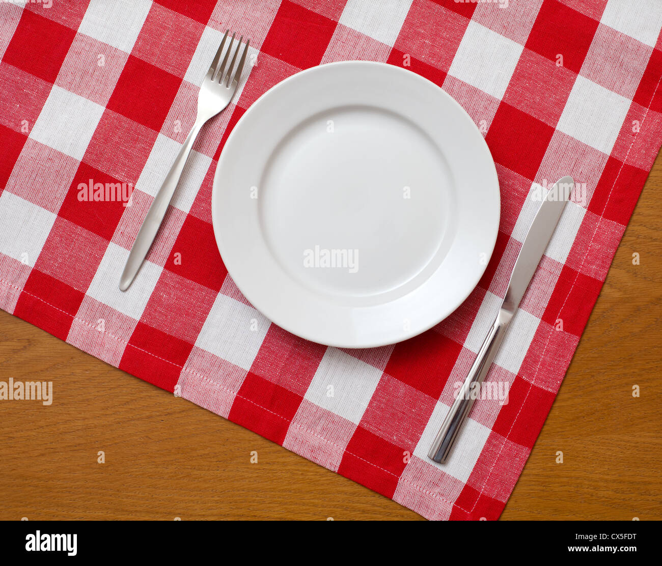 Couteau, fourchette et plaque blanche sur table en bois avec nappe rouge vérifié Banque D'Images