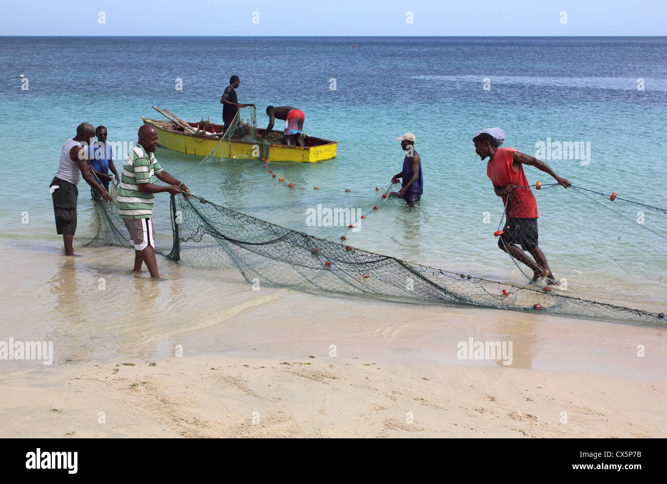 Les pêcheurs des Caraïbes Contrôle et remise à zéro leurs filets dans leur bateau, plage de Grand'Anse, La Grenade. West Indies. Banque D'Images
