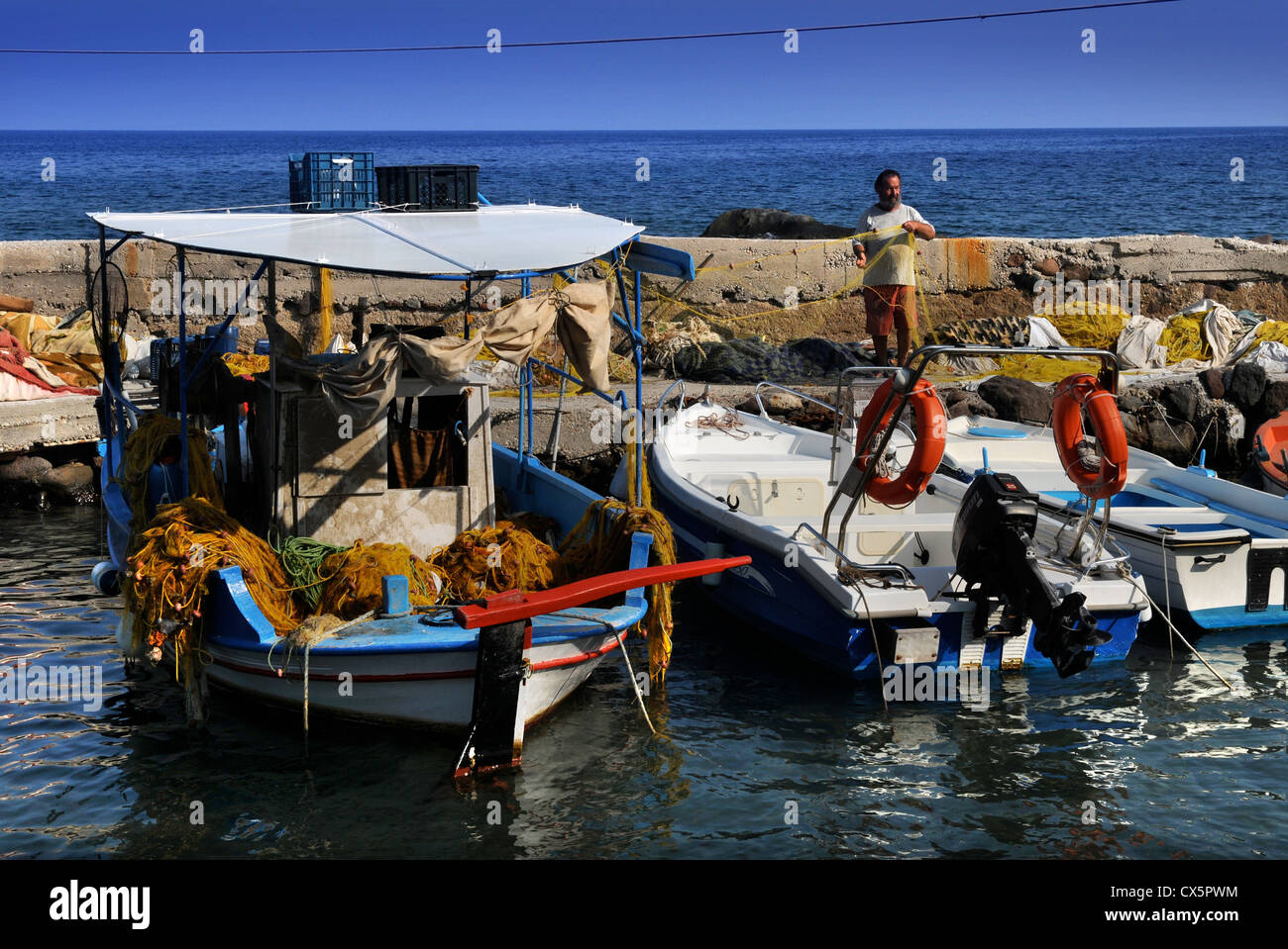 Un pêcheur qui tend à ses filets sur le port de portes sur l'île d'Egine Grèce Banque D'Images