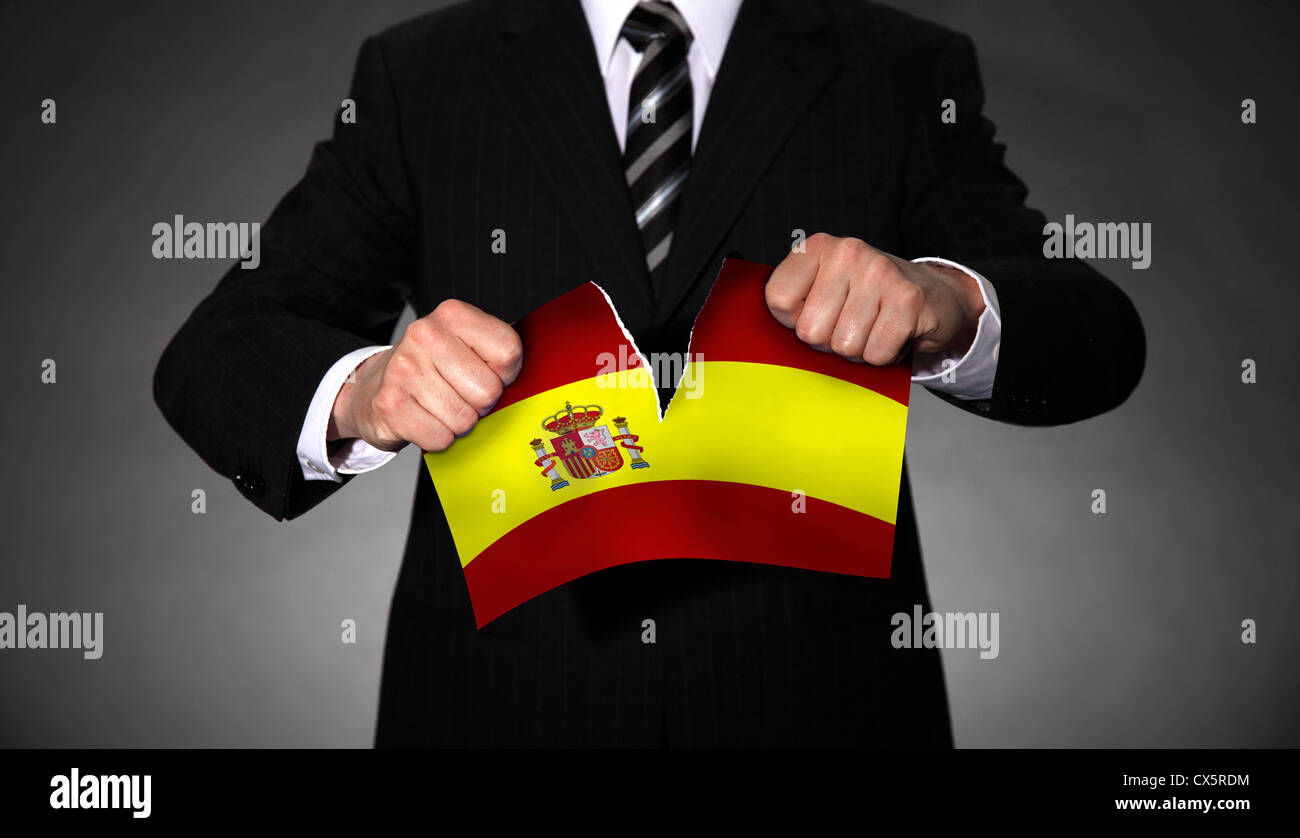 Homme en costume en train de détruire le drapeau national de l'Espagne. Banque D'Images