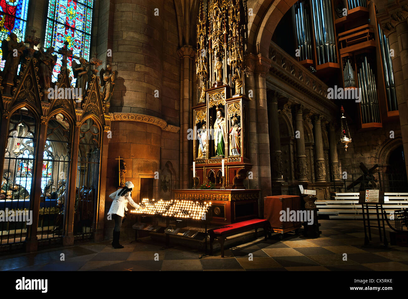Une femme allume une bougie dans la cathédrale gothique de Frieburg dans le Black Forest, de l'Allemagne. Banque D'Images