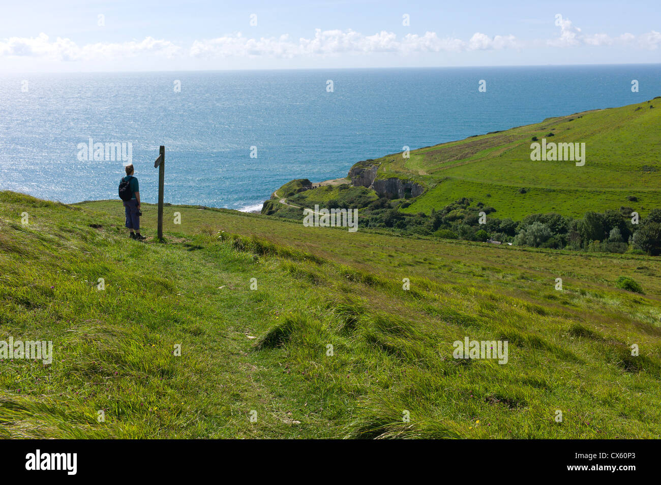 Walker sur chemin côtier surplombant la mer depuis les collines verdoyantes surplombant la mer, Worth Matravers, Dorset, England, UK Banque D'Images