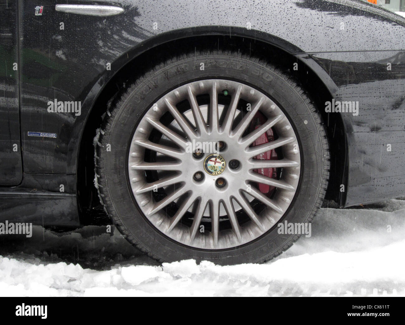 Pneus d'hiver sur une voiture familiale conduire dans la neige. Ce British Alfa est dans les Alpes Suisses sur pneus temps froid, remarque la bande de roulement profonde Banque D'Images