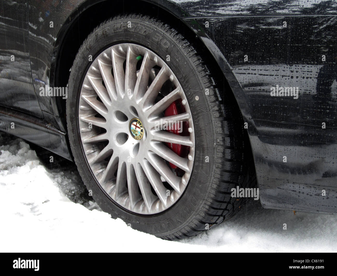 Pneus d'hiver sur une voiture familiale conduire dans la neige. Ce British Alfa est dans les Alpes Suisses sur pneus temps froid, remarque la bande de roulement profonde Banque D'Images