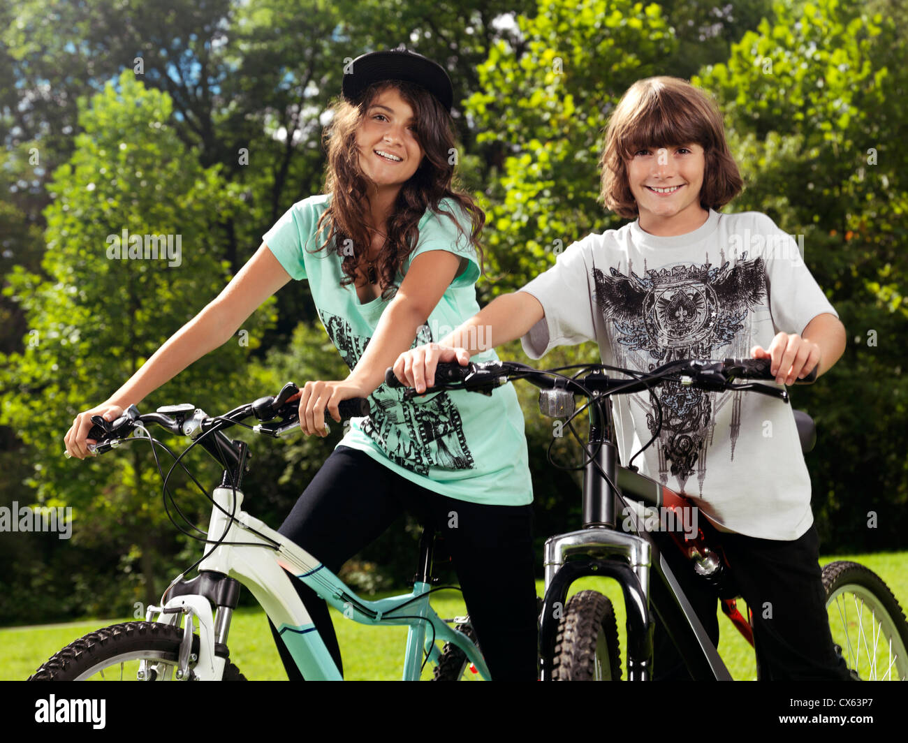 Deux happy smiling children sur leur bicyclette dans un parc, frère et soeur, 10 et 13, profitant de la journée d'été ensoleillée. Banque D'Images