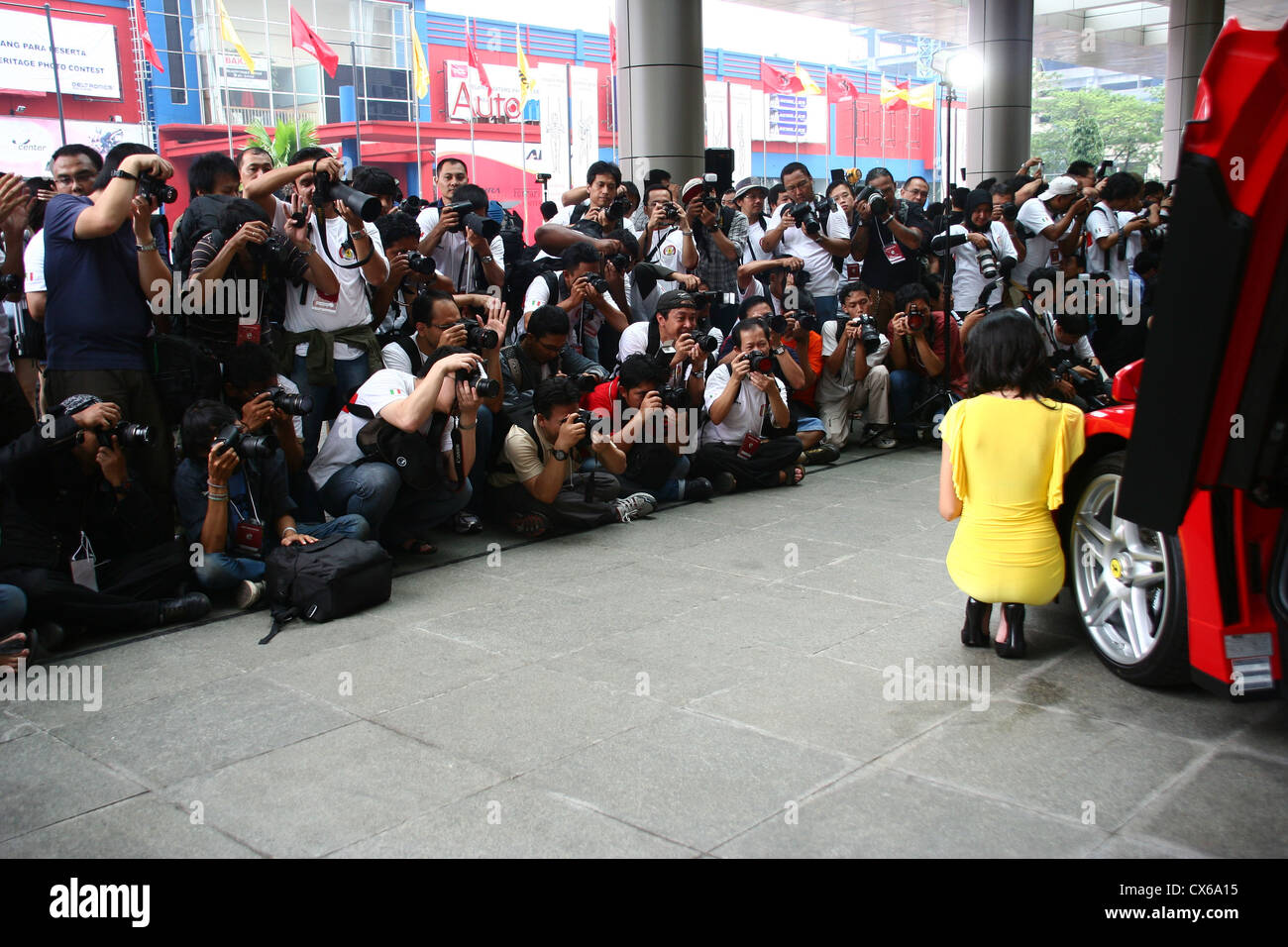De très nombreux photographes photographier un modèle féminin avec rouge Ferrari voiture de sport. Banque D'Images