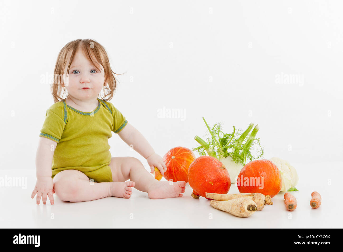 Une fille de bébé assis avec des légumes Banque D'Images