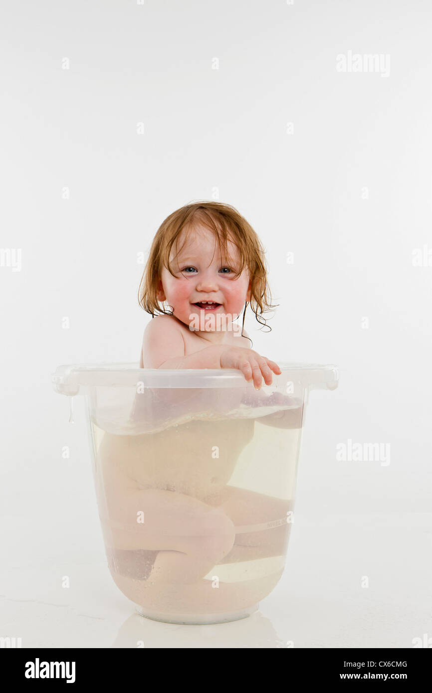 Une petite fille dans un seau d'eau Banque D'Images