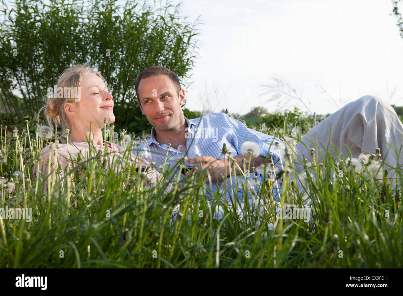 Un couple allongé dans l'herbe d'un vin rouge Banque D'Images
