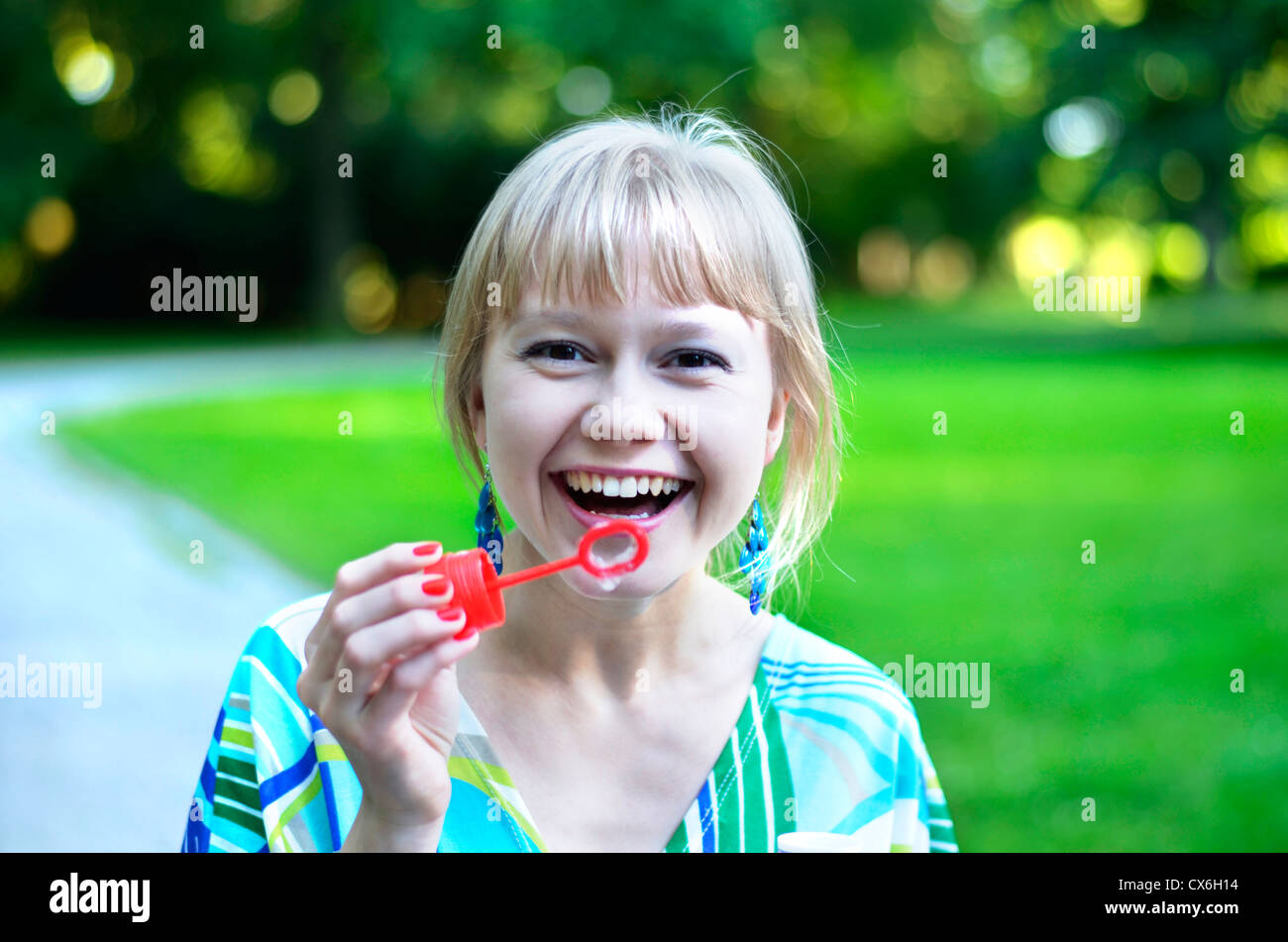 Une belle jeune fille est vraiment heureux après qu'elle a si bien réussi à faire des bulles de savon. Banque D'Images