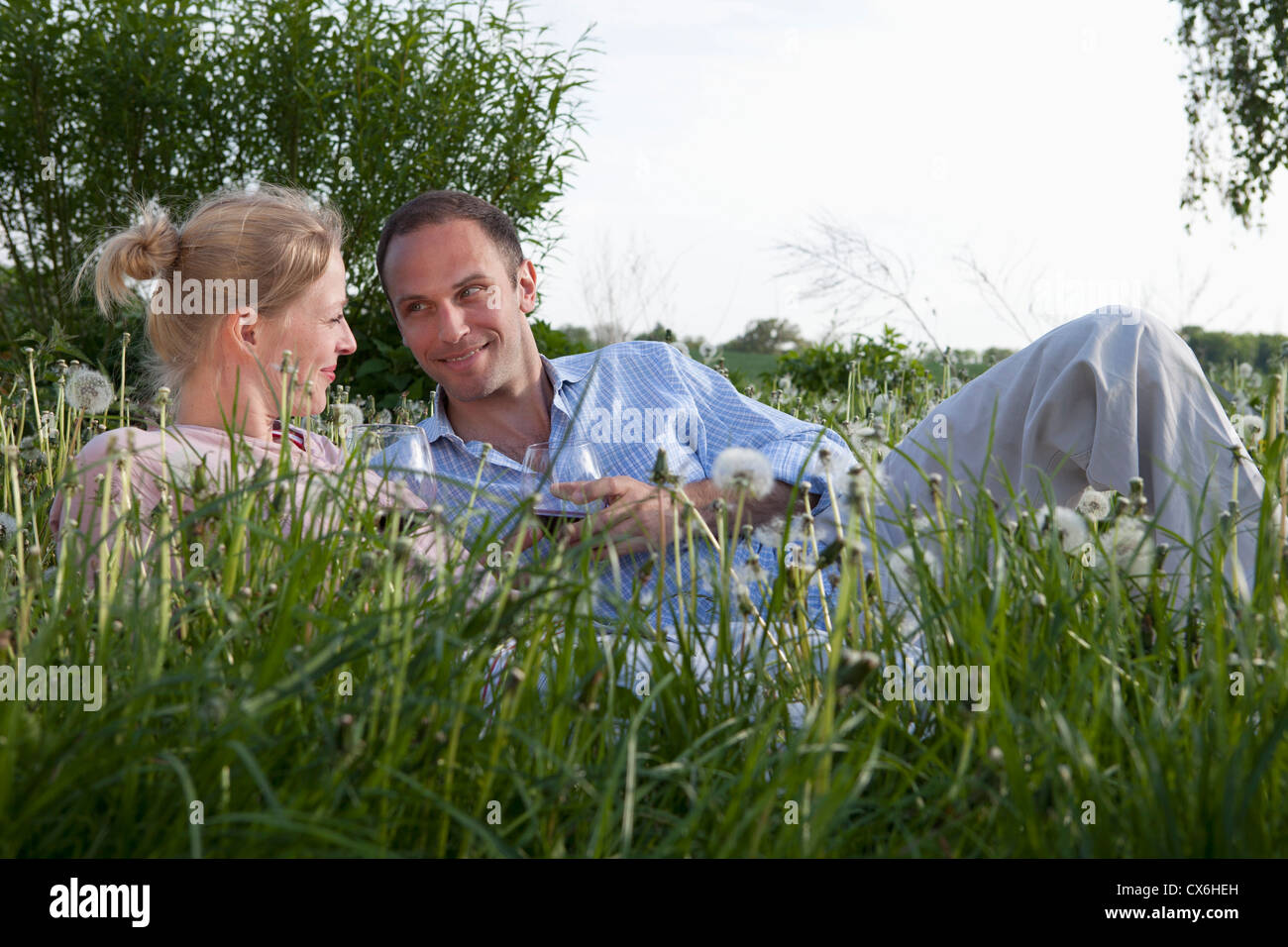 Un couple allongé dans l'herbe d'un vin rouge Banque D'Images