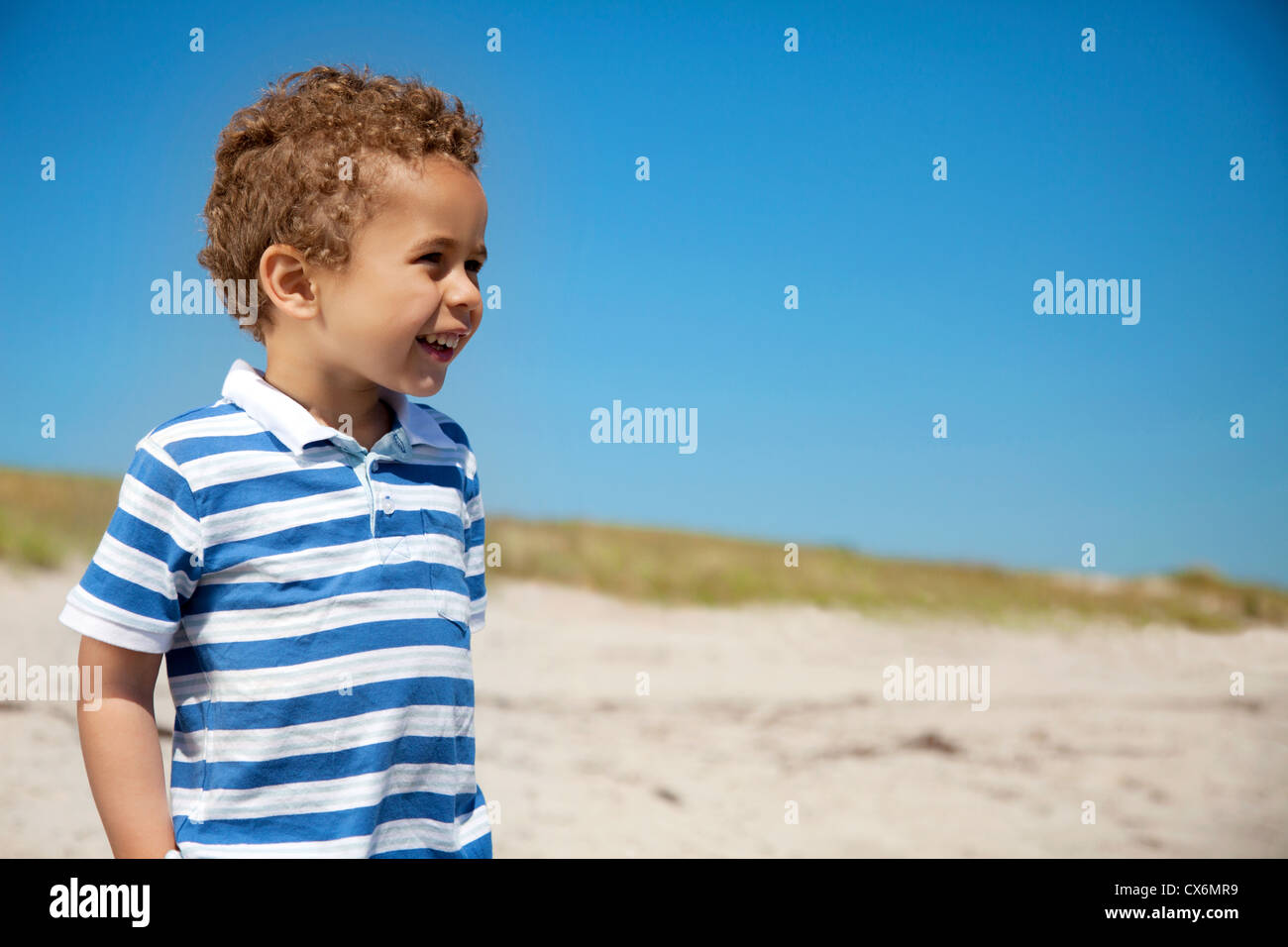 Adorable petit garçon profitant du plein air contre le ciel bleu Banque D'Images